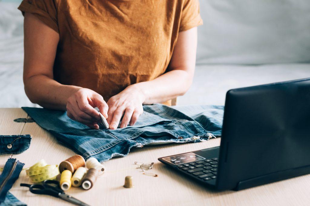 Une femme suit une formation en ligne et regarde des cours de couture sur un ordinateur portable. Concept d'apprentissage en ligne branché permettant de suivre des cours à domicile. Passe-temps de couture à domicile